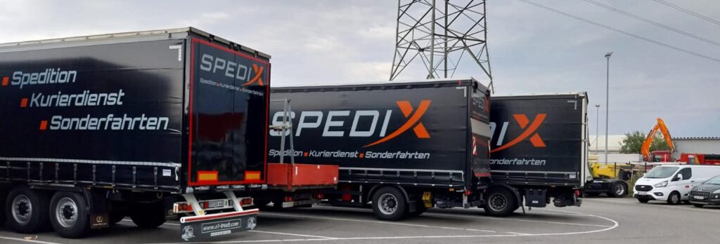 Drei gebrandete Spedix LKW-Auflieger mit Planenverdeck nebeneinander auf dem Speditionshof bereit für den FTL- und LTL-Transport.