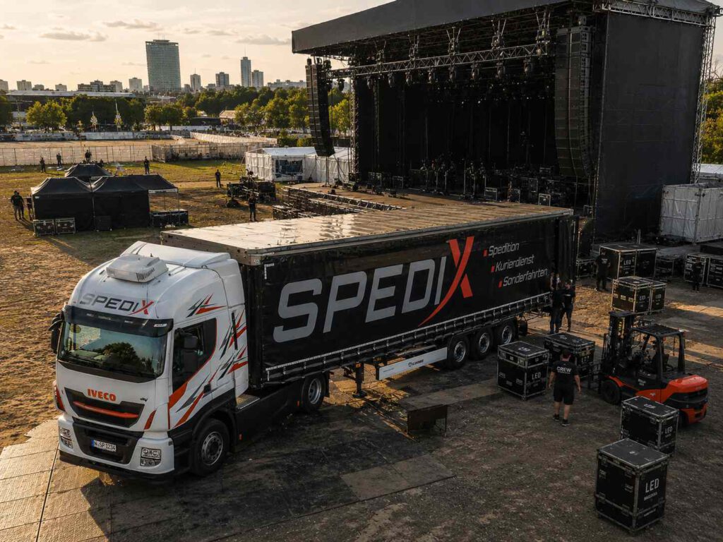 Ein Spedix GmbH LKW bei der Anlieferung von sensibler Veranstaltungstechnik für eine Eventlogistik-Bühne.
